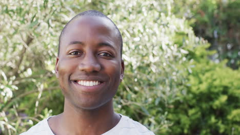 a young african american man is smiling broadly outdoors