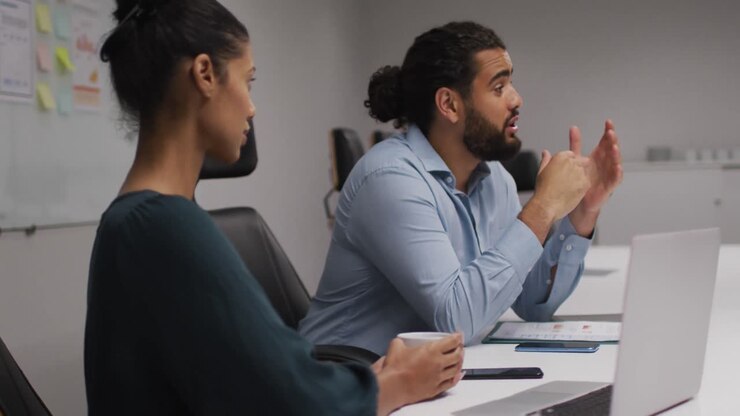 Middle eastern man talking to his his female colleague in meeting room at office