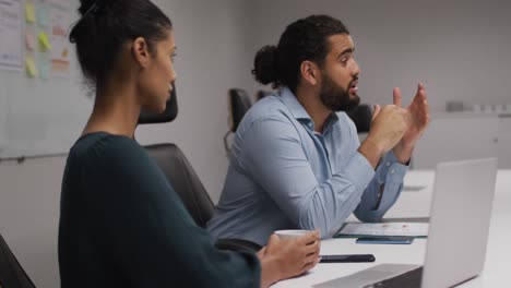 middle eastern man talking to his his female colleague in meeting room at office