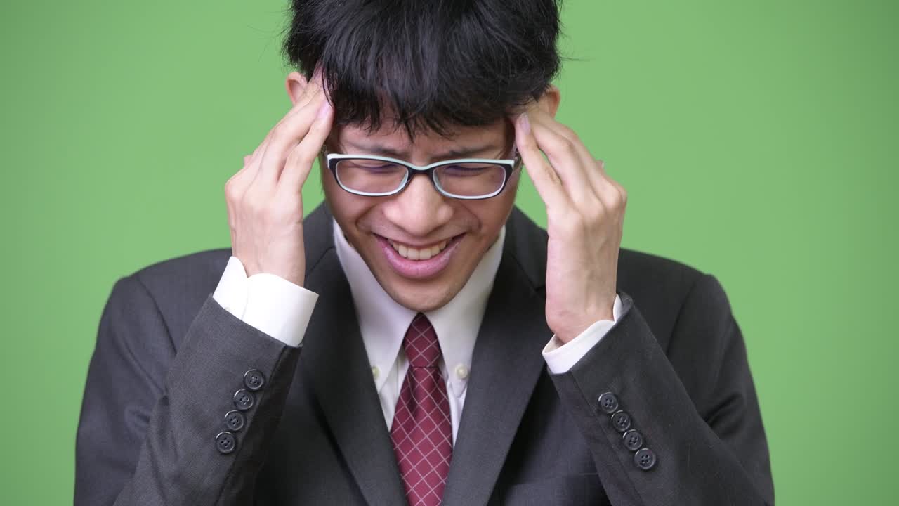 머리가 아프고 있는 젊은 스트레스를 받은 아시아 사업가