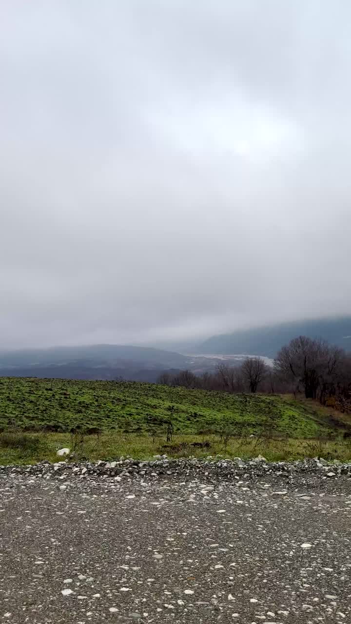 Remote village homes near forest with grassy terrain and foggy sky. Guba, Azerbaijan