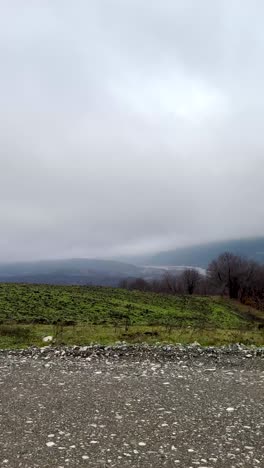 remote village homes near forest with grassy terrain and foggy sky. guba, azerbaijan
