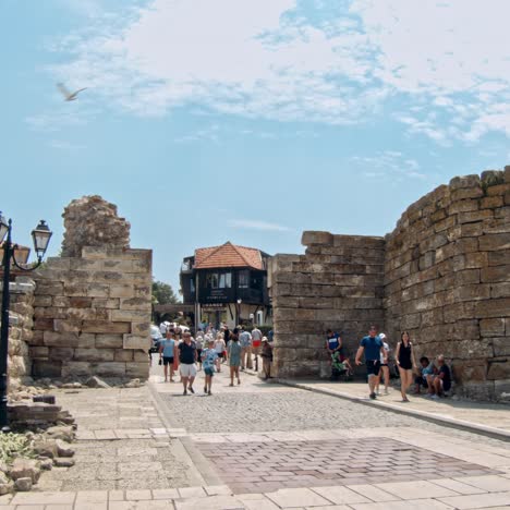 people walking through an old city gate on a sunny day