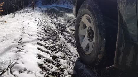 4x4 車輛的左前輪在冬天在山上雪地路上行駛,近距離