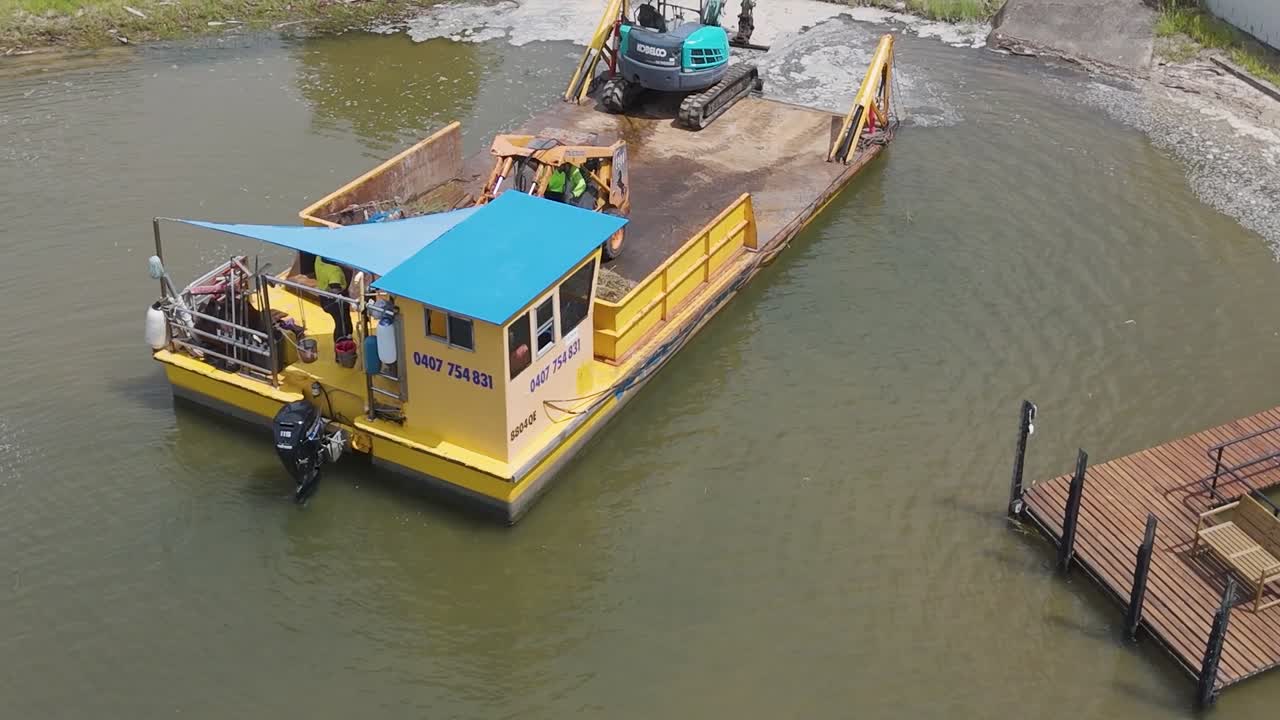 vista aérea de una barcaza con una grúa trabajando en un canal cerca de casas de lujo, mostrando la construcción urbana