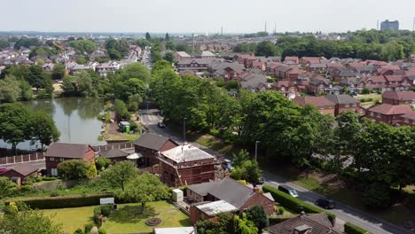 desarrollo de barrio de casas de ladrillo rojo británicas con vista aérea del lago mientras los constructores trabajan en la renovación del techo