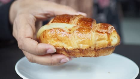 woman holding a cheese croissant