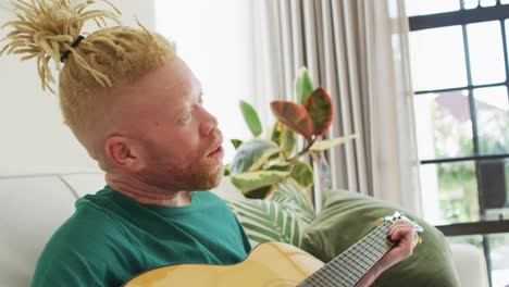 albino african american man with dreadlocks playing guitars and singing