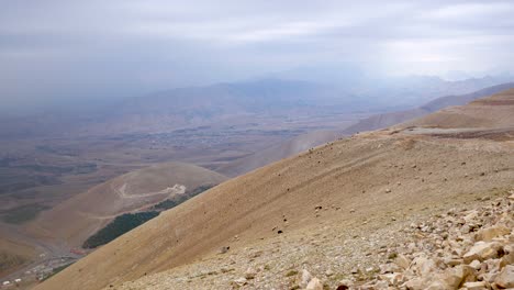 black and white sheep climbing up a steep mountain with a town in the far distance