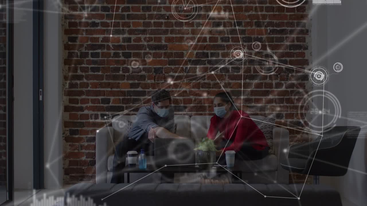 Applications icons connecting with lines, graphs over coworkers in masks discussing over laptop