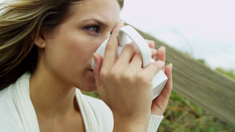 young blonde female drinking coffee outdoors fall beach