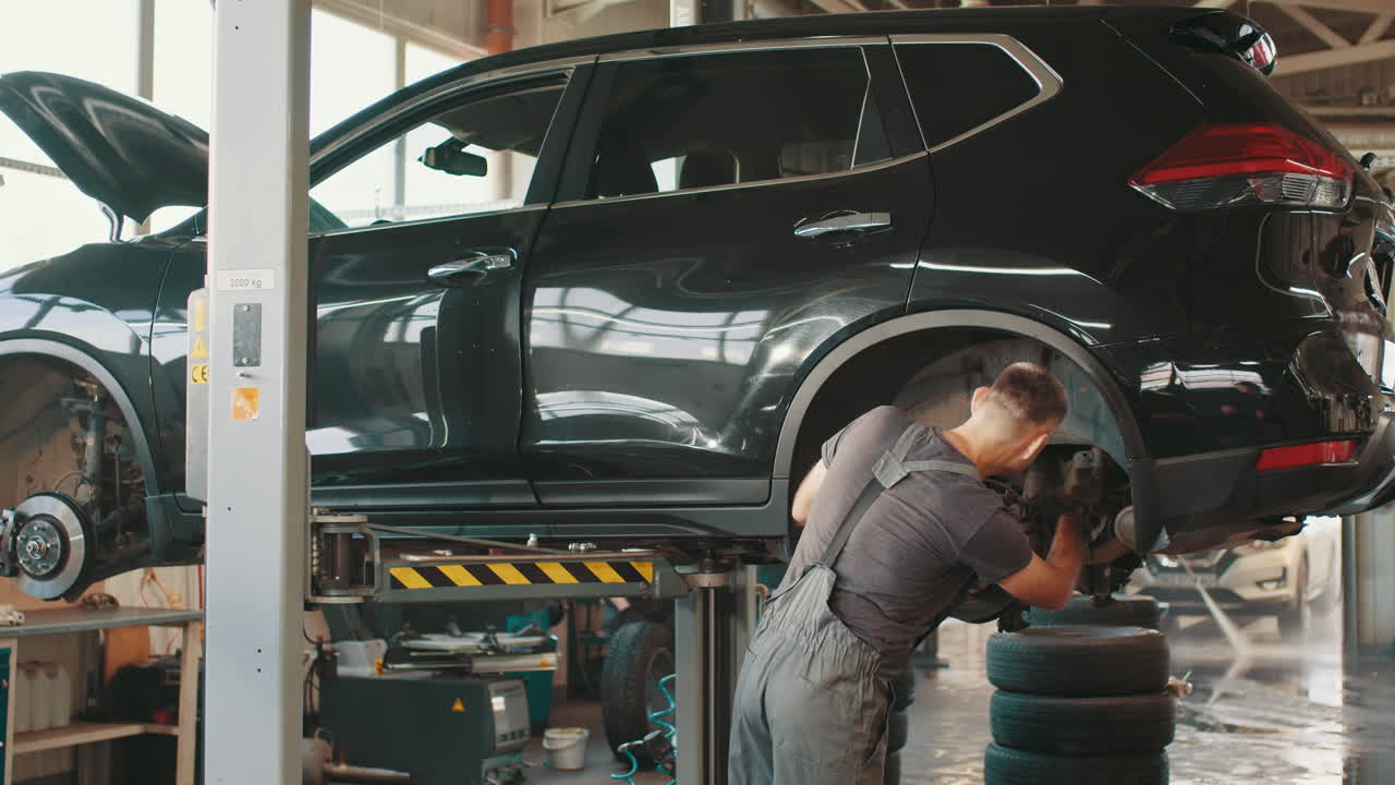 mecánico de automóviles trabajando en un suv negro en un garaje