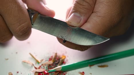 Footage-of-hands-slowly-sharpening-a-pencil-and-some-coloured-pencils-with-a-sharp-knife