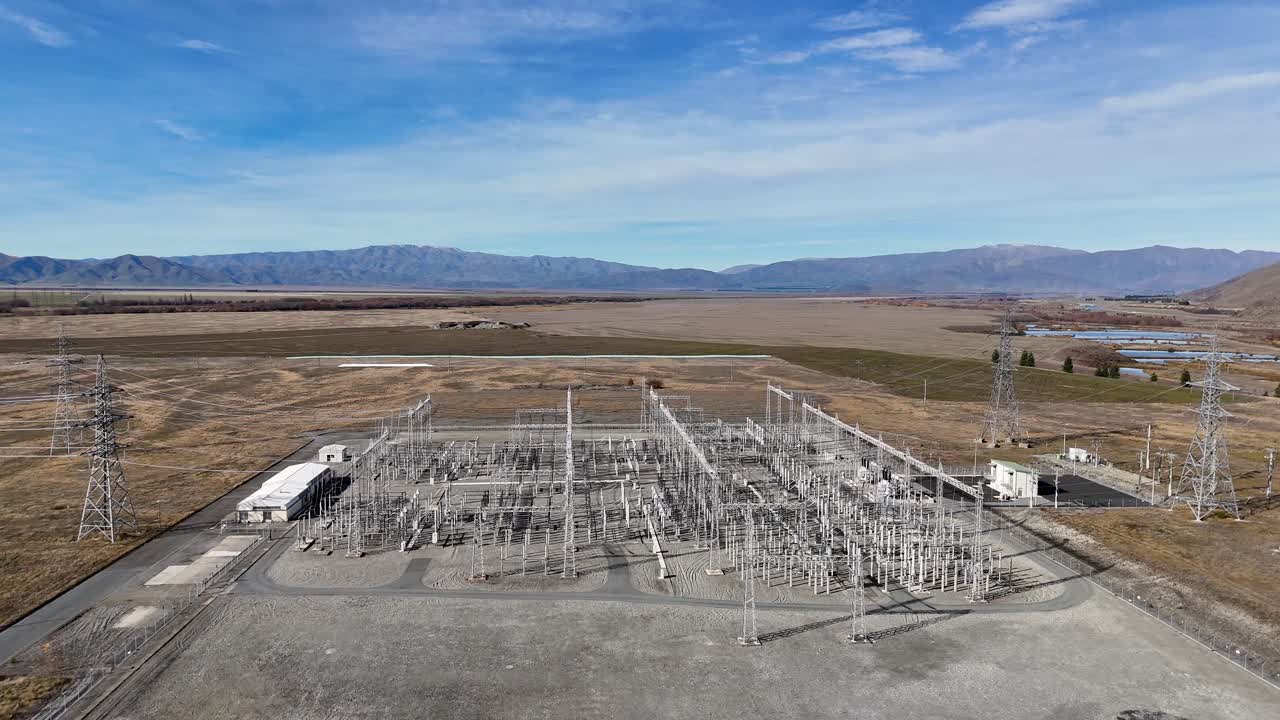 Drone footage captures an expansive electrical substation under clear skies at Lake Tekapo, showcasing infrastructure amidst natural landscapes