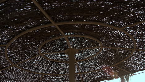 bottom up view of cane umbrella. sky background through straw sunshade.