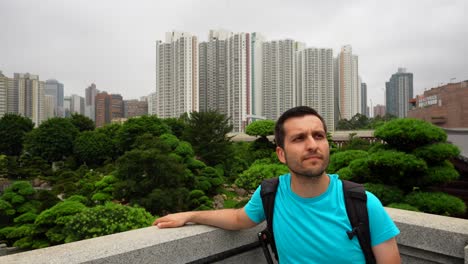 tourist admires the lush greenery of nan lian garden with towering hong kong skyscrapers in background