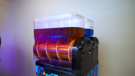 slushy machine spinning red liquid sirup freshly put in to mix into frozen drink isolated with white background placed indoor for event to treat guests slow motion