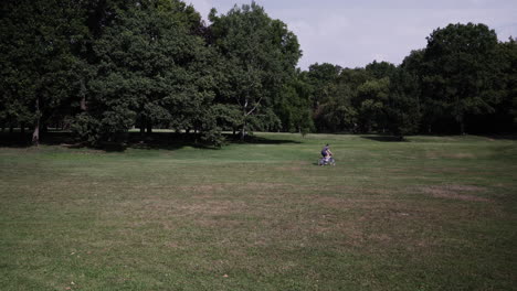 a man rides his bike through a grassy field in a park