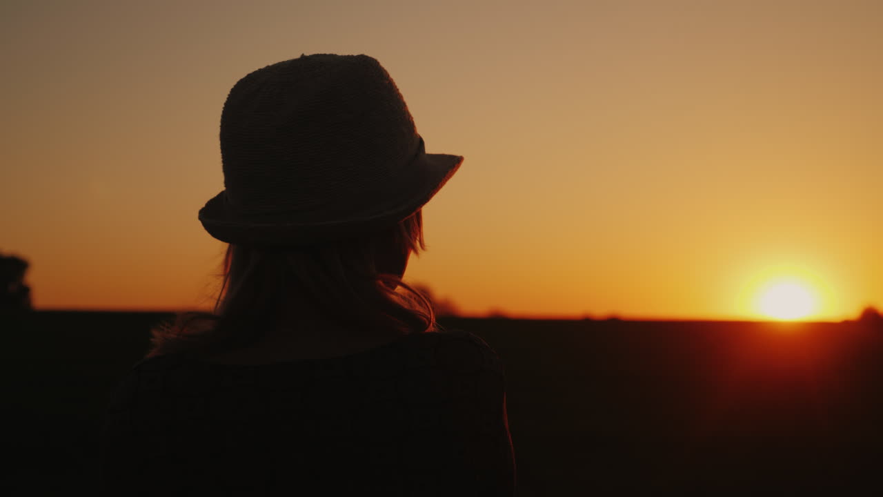 모자를 쓴 한 여성은 일몰 희망과 밝은 미래 개념 4k 슬로우 모션 비디오를 기대합니다