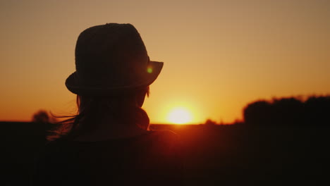 a woman in a hat looks forward to the sunset hope and bright future concept 4k slow motion video