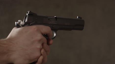 primer plano de una pistola de pequeño calibre retenida por un hombre caucásico