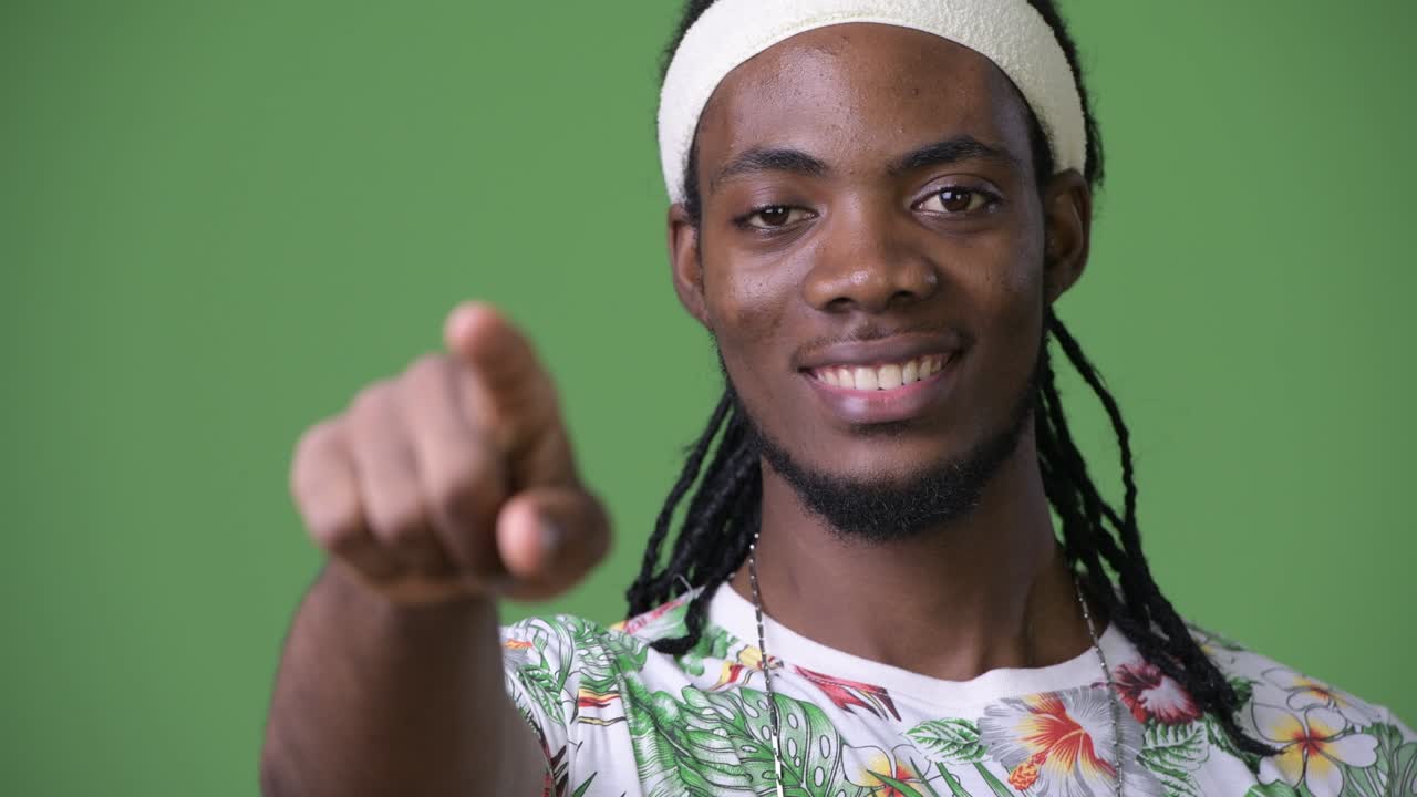 joven hombre africano guapo con dreadlocks contra un fondo verde