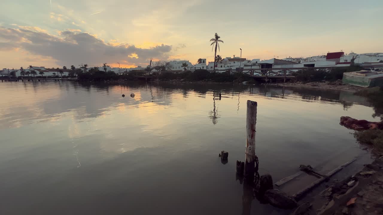 Sunset over a canal with wooden pier and houses