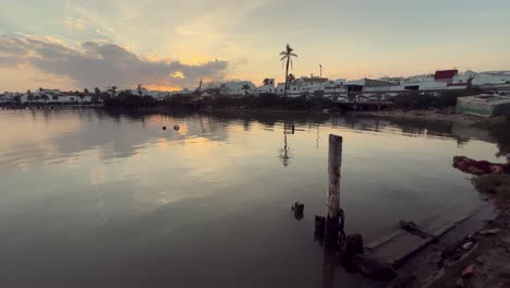 sunset over a canal with wooden pier and houses