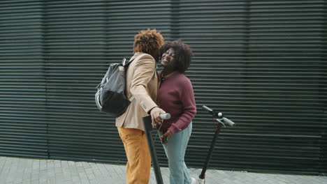 african american friends with e-scooters meeting on street and chatting