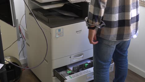 Focused-man-working-with-a-printer-in-the-office-on-a-productive-workday