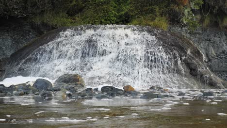 Slow-motion,-medium-shot-of-a-waterfall-flowing-into-the-ocean