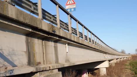 long bridge supported by large reinforced concrete pillars seen from the side with vegetation underneath