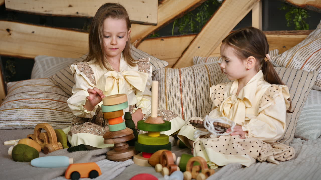 Two little girls playing with wooden toys on the bed. Ecological and sustainability concept