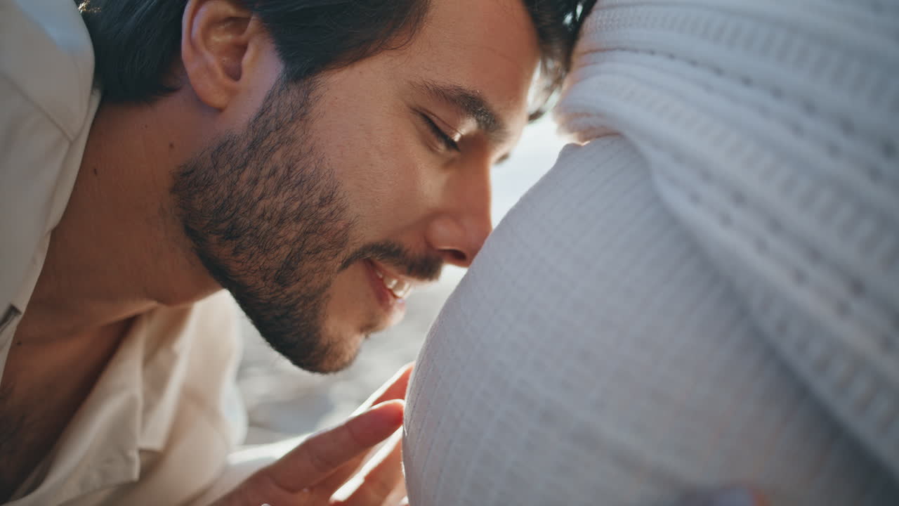 임신한 아빠가 말하고 배가 임신한 아내가 미소 짓고 가까이서 사랑을 느다.