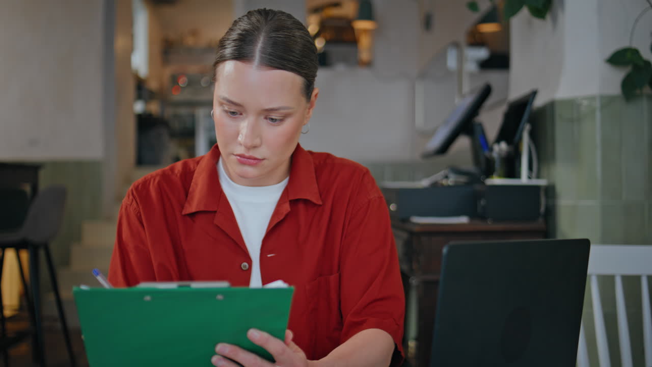 Restaurant staff reviewing paperwork sitting table with clipboard closeup