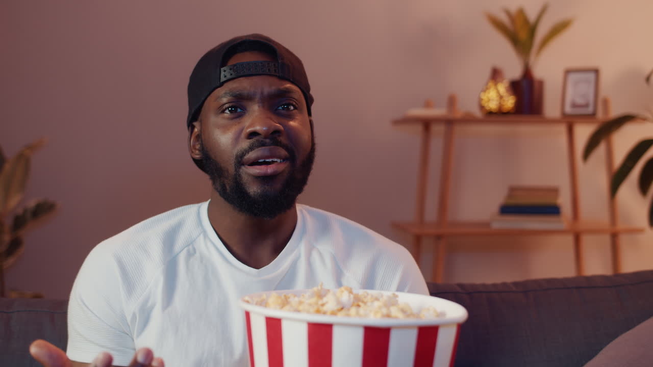 Man watching television and eating popcorn