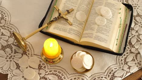 communion hosts lit candle and holy bible cross with jesus