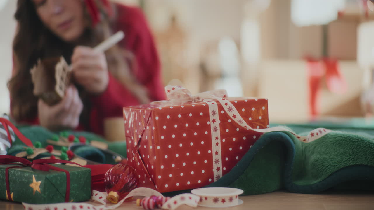 regalos de navidad en el suelo con la mujer coloreando el adorno de la casa en casa
