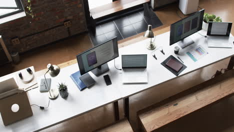 multiple workstations with laptops, smartphones, and desk lamps in a business setting