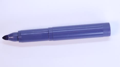 purple marker pen rotating on white surface background, macro shot close up view detail