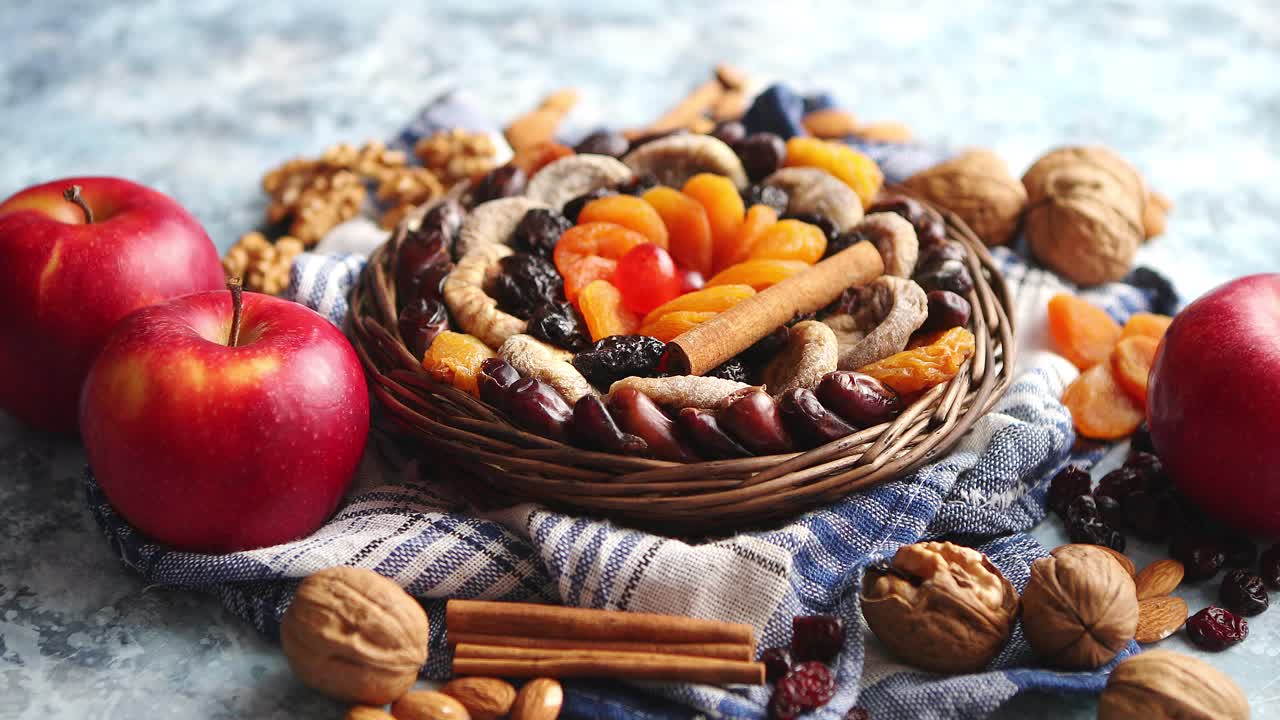 Composizione di frutta essiccata e noci in una piccola ciotola di vimini, posizionata su un tavolo di pietra.
