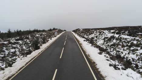 Antena-De-Largo-Camino-En-La-Distancia-A-Través-De-Highland-Campo-Nevado-Páramos-Empuje-Hacia-Adelante-Bajo