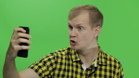 caucasian young man in yellow shirt taking nice selfies on the smartphone