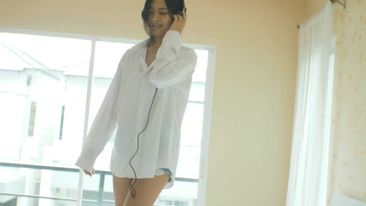 젊은 아시아 여성들이 침대에서 음악을 듣고 있습니다.