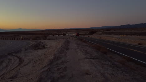 trucking with cargo on freeway in salton sea desert with glowing sky at dusk , california - static