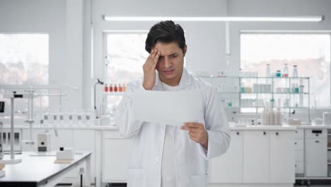 científico indio estresado leyendo artículos de investigación