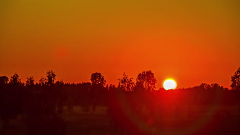 Una-Puesta-De-Sol-Brillante-Y-Ardiente-Sobre-El-Campo-Se-Vuelve-Naranja-Al-Atardecer---Lapso-De-Tiempo