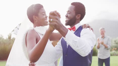 happy african american couple holding hands and dancing during wedding