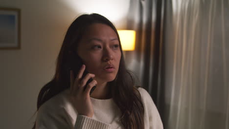 Angry-Anxious-Or-Stressed-Woman-Spending-Evening-At-Home-In-Lounge-Talking-On-Mobile-Phone