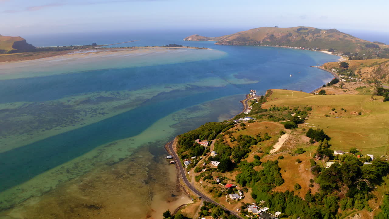 Aerial view of a coastal town and bay with clear water and hills